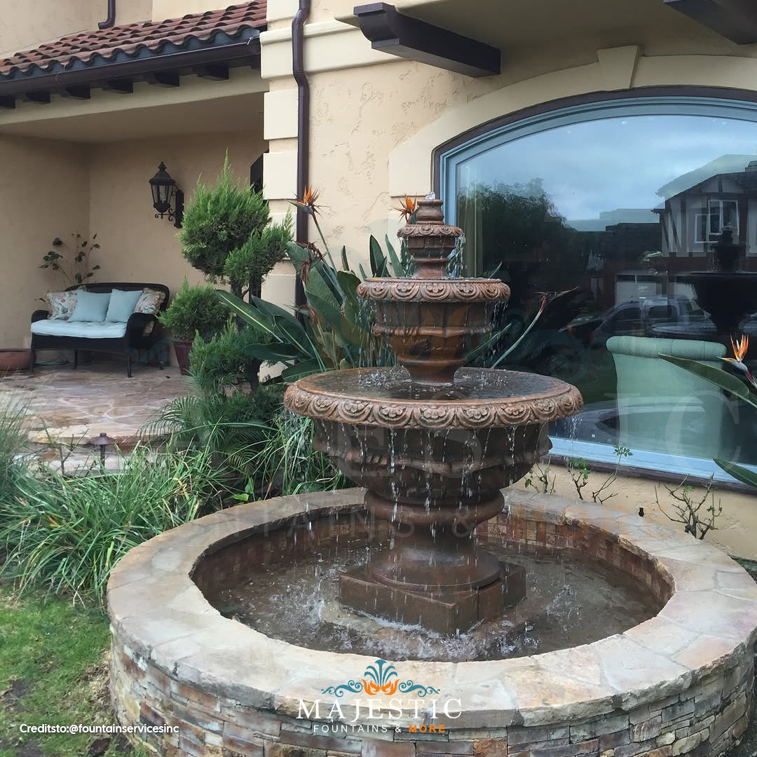 Fiore Stone Roma Fountain 234-F in cast stone on a patio with water flowing into a stone basin near a large window